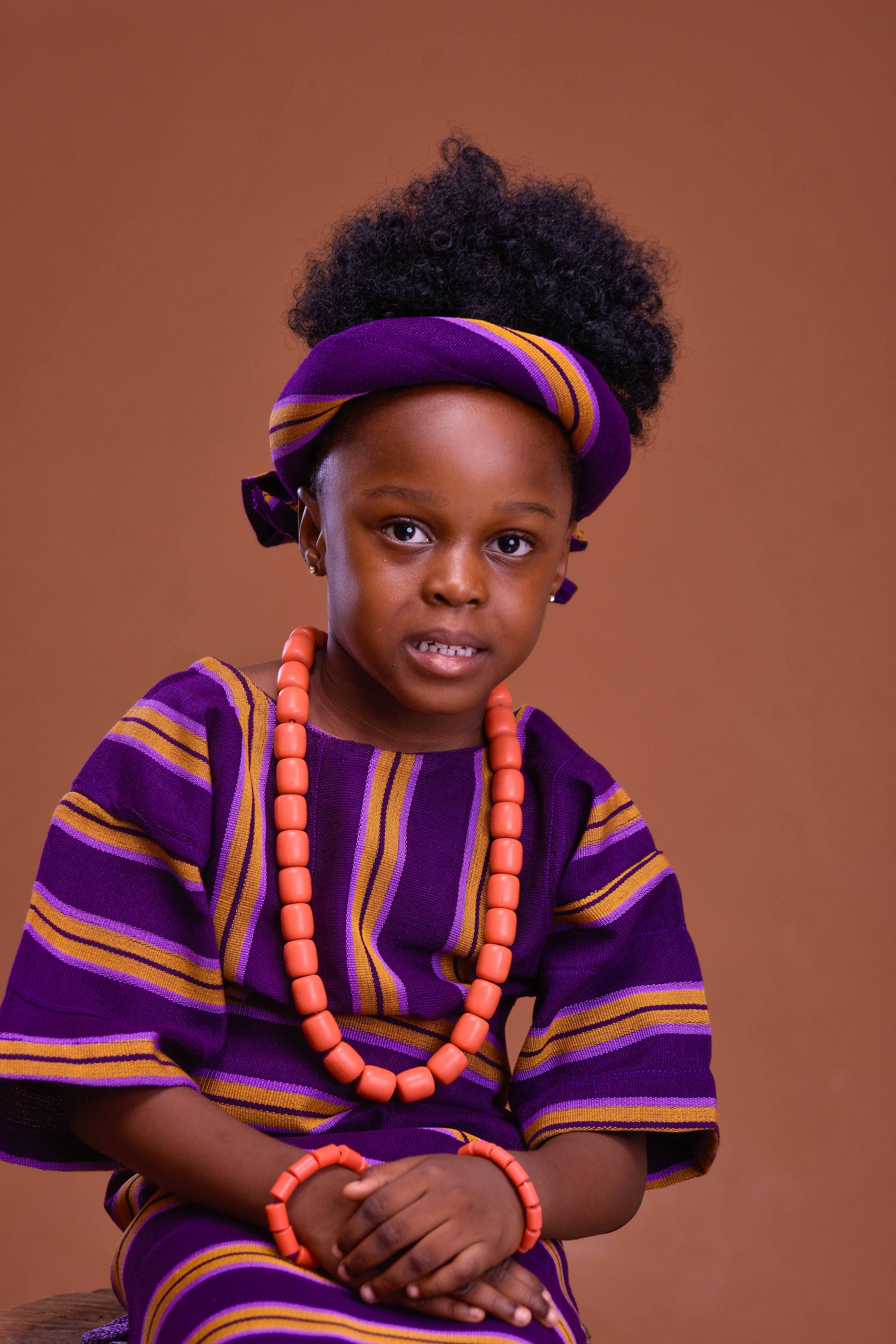 Adorable child in vibrant African traditional dress and jewelry, showcasing cultural heritage and joy.