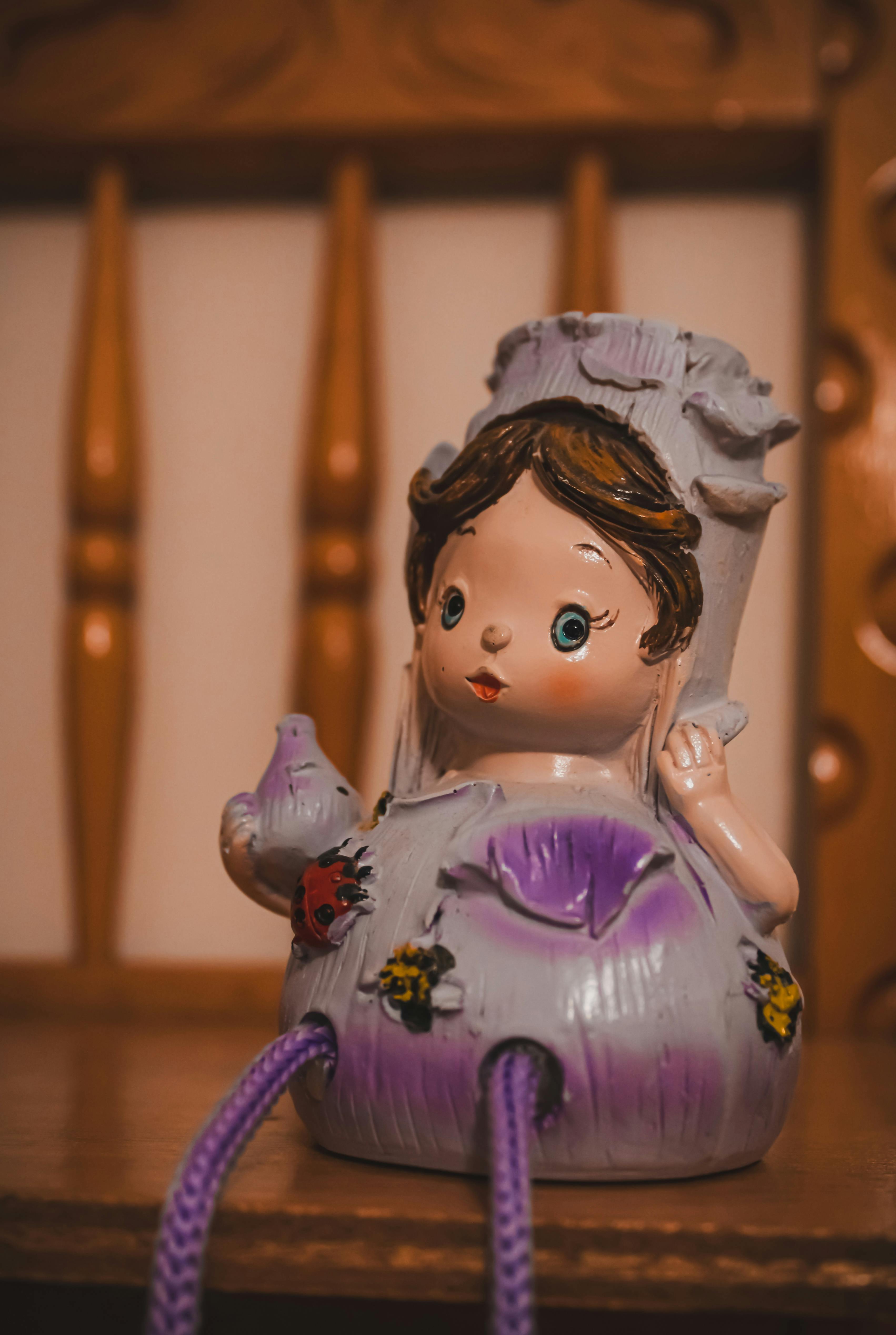 a ceramic doll sitting on a shelf with purple hair