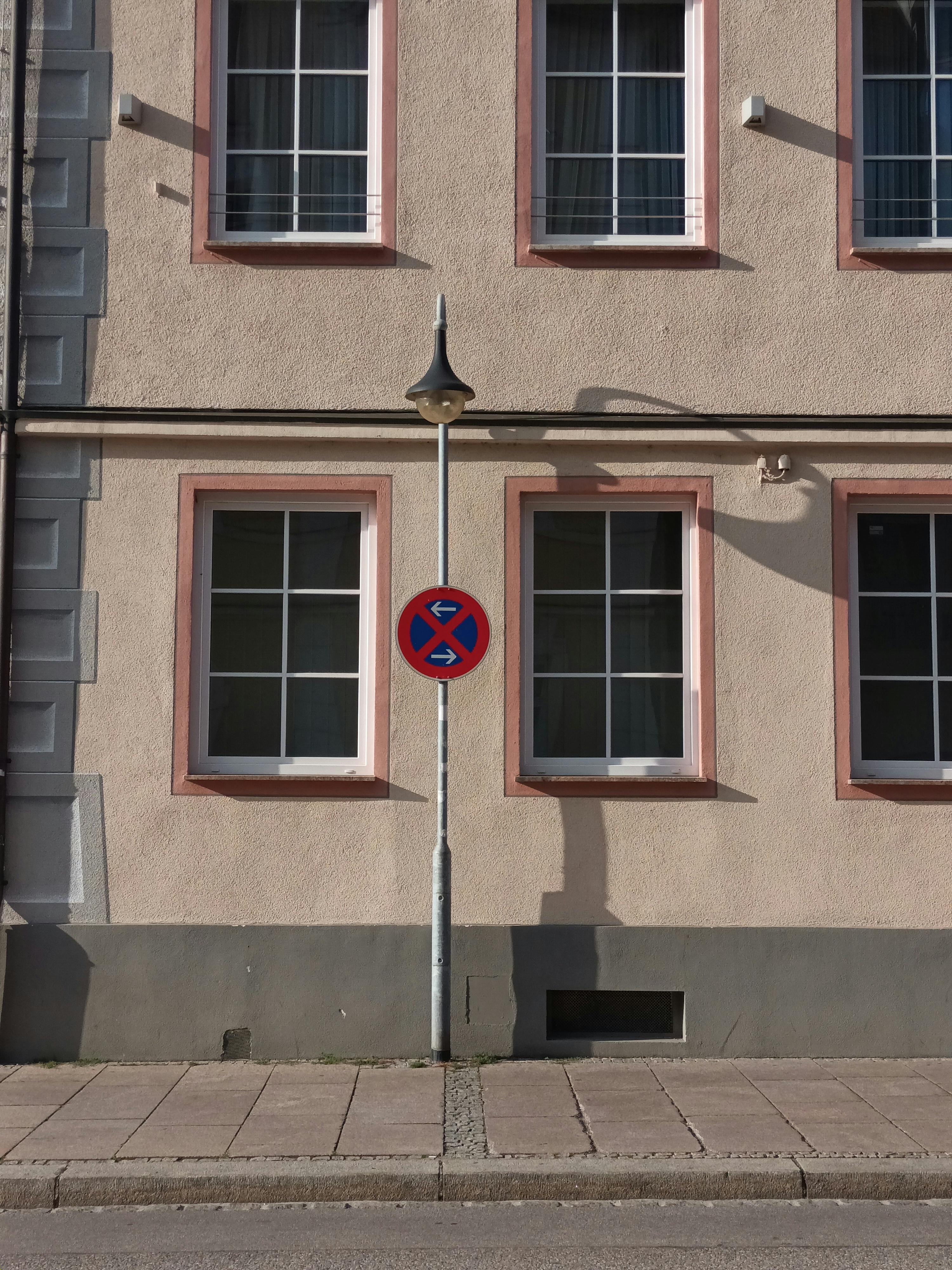 Street view of a building facade featuring a no parking sign and multiple windows.