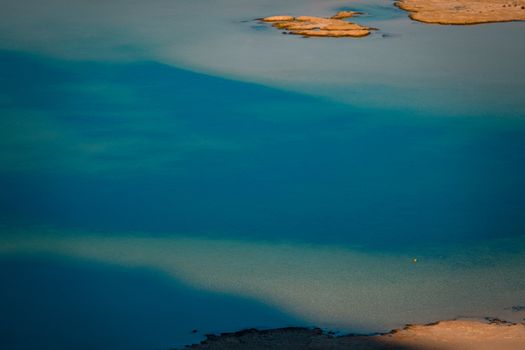 A serene aerial shot capturing the tranquil turquoise waters of a lake under the sunlight.