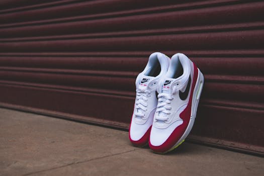 Stylish white and red sneakers leaning against a closed metal shutter, showcasing footwear design.