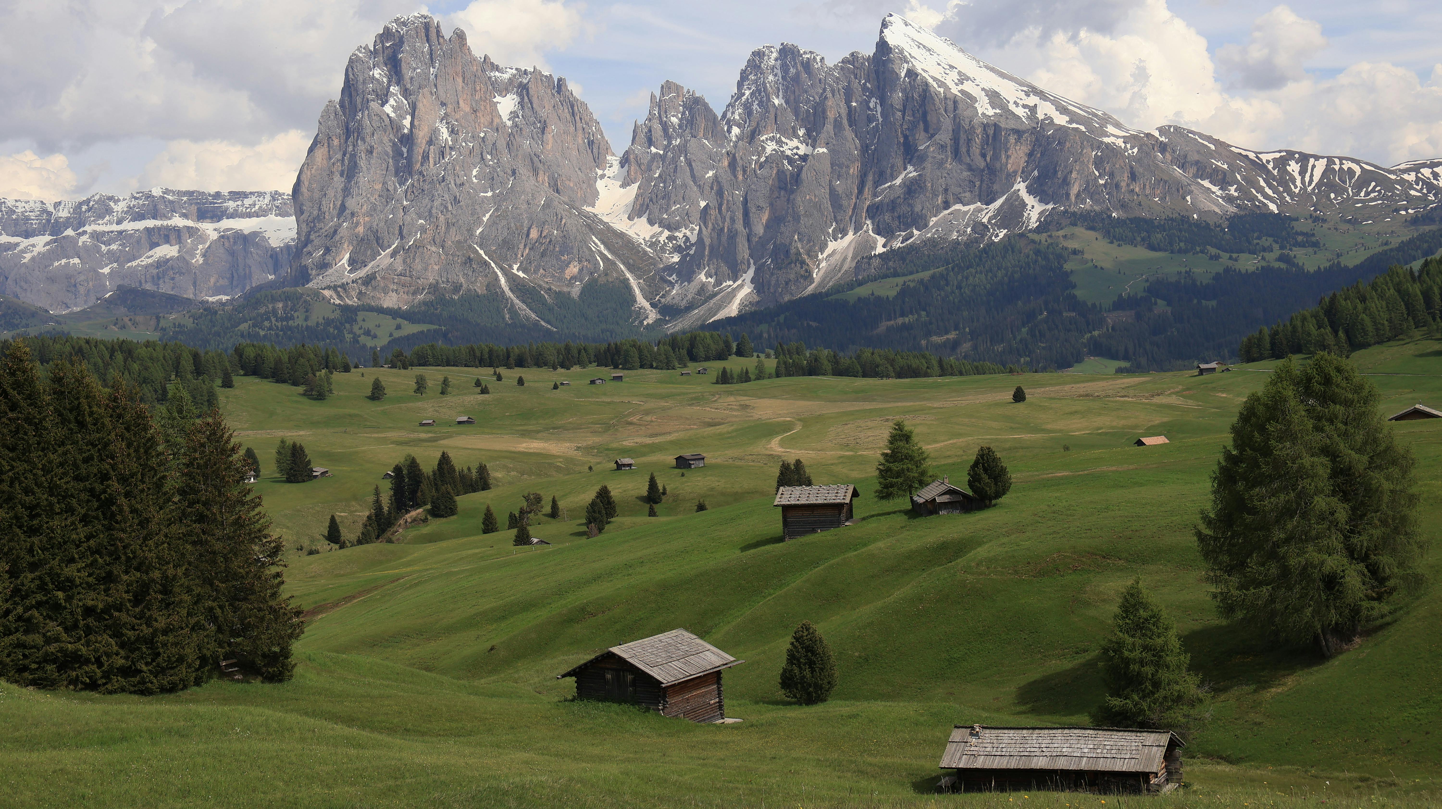 Idyllic summer landscape of Alpe di Siusi with wooden huts and the Dolomites.