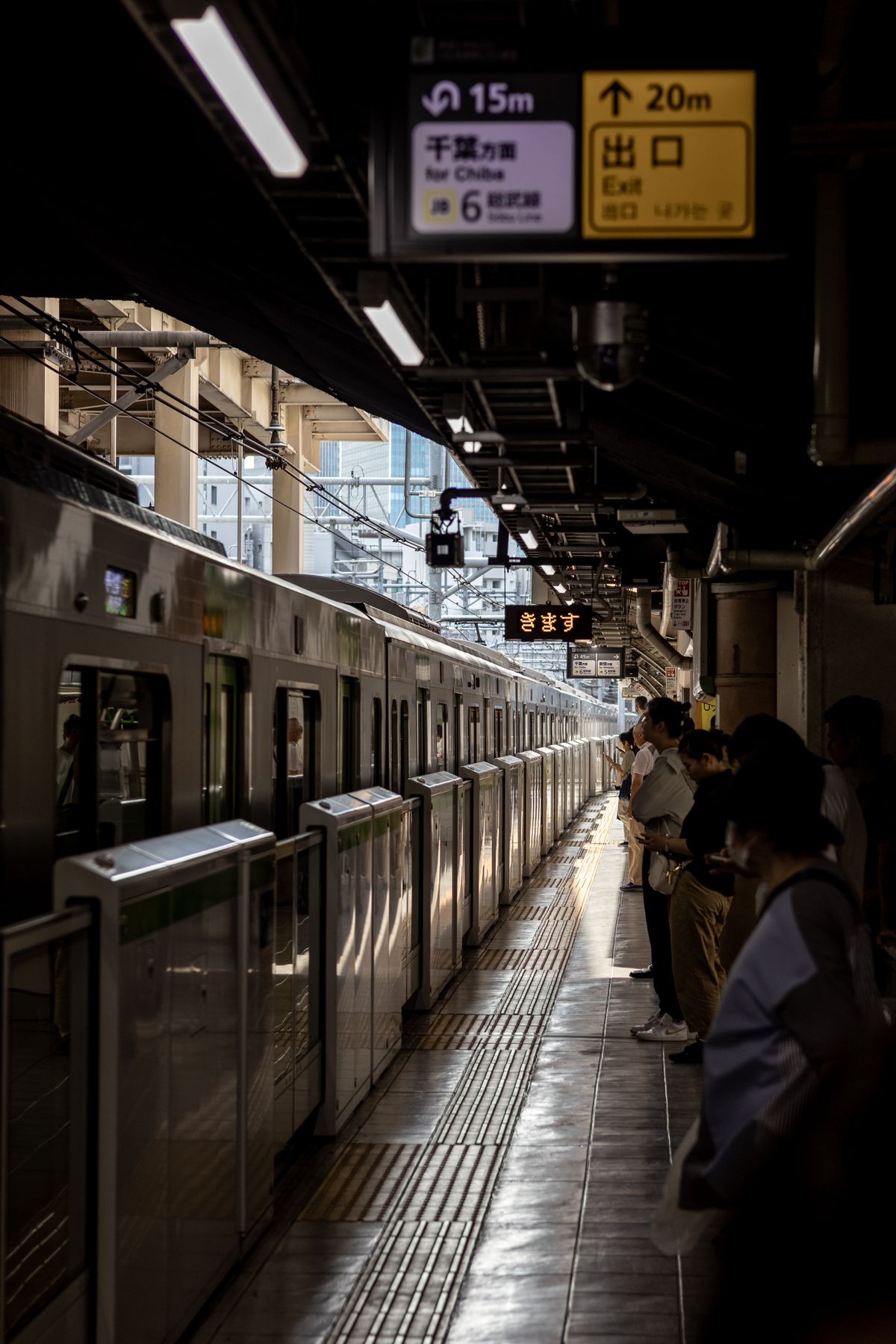 Passengers waiting at a Tokyo train station platform for a train
