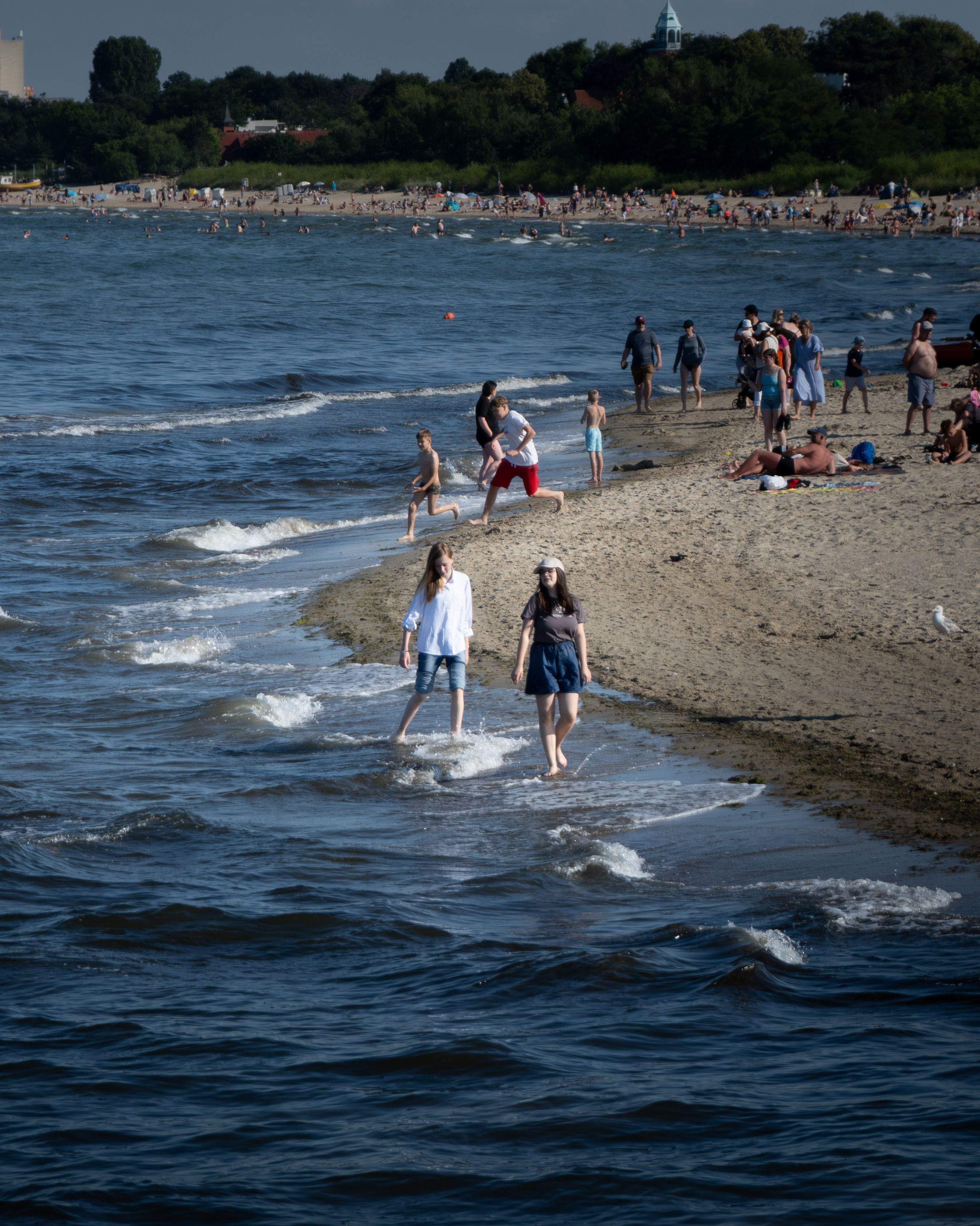 People enjoying a sunny day at the beach with water activities and relaxing on the sand.