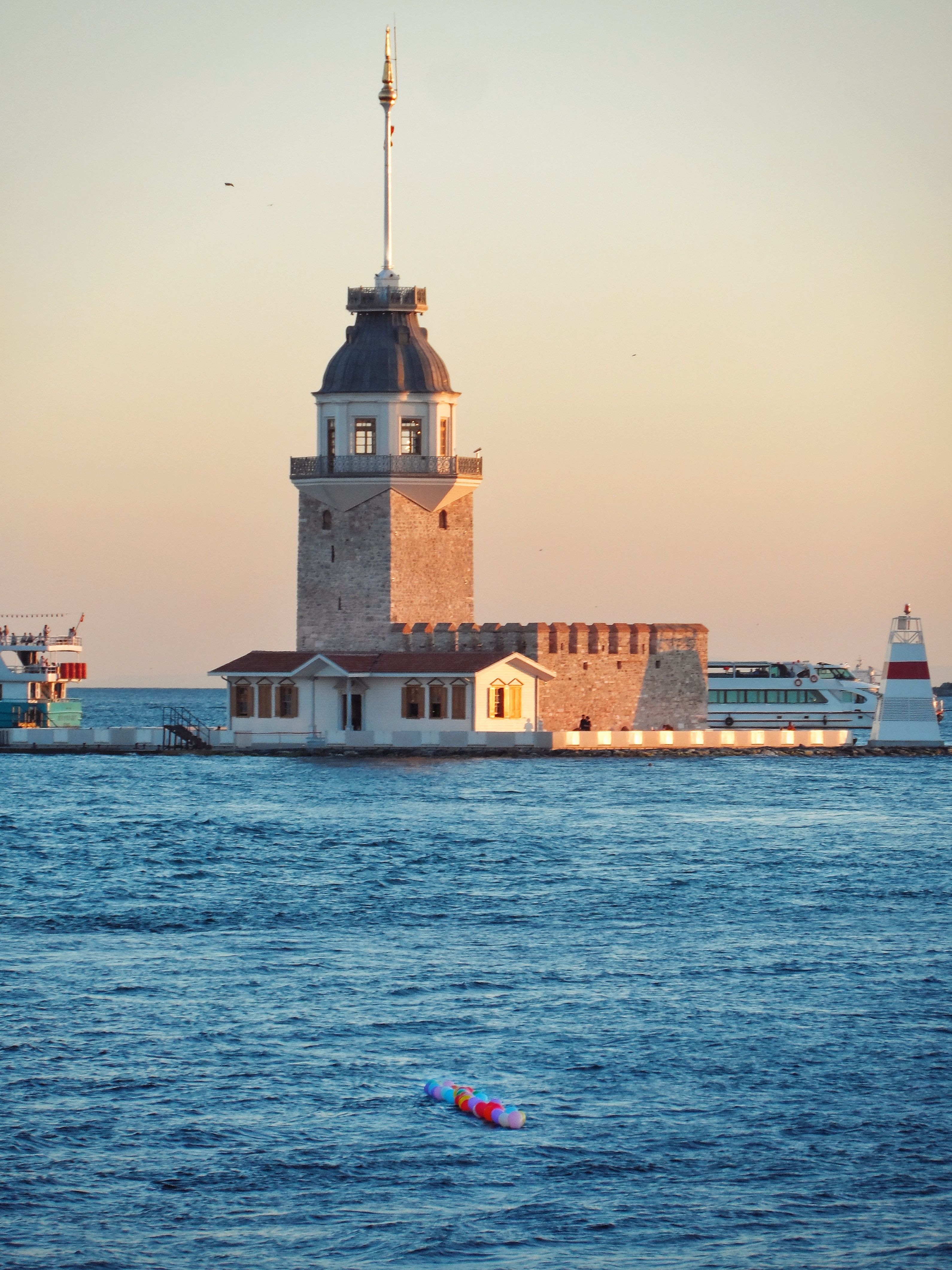 A boat is floating in the water near a lighthouse · Free Stock Photo