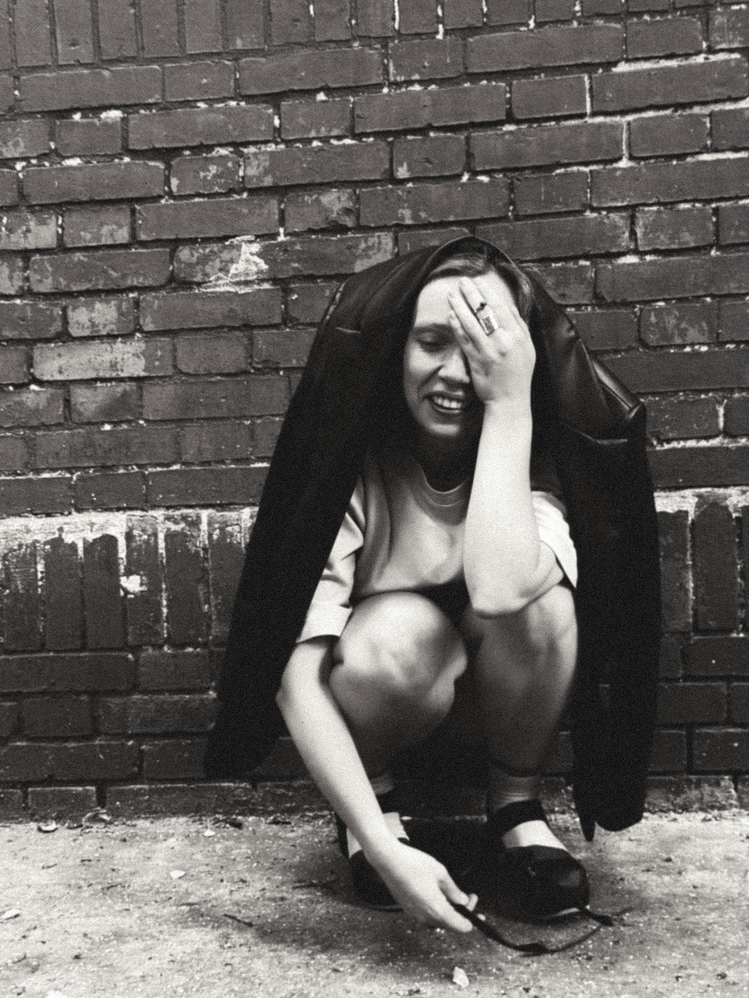 a woman crouching down in front of a wall