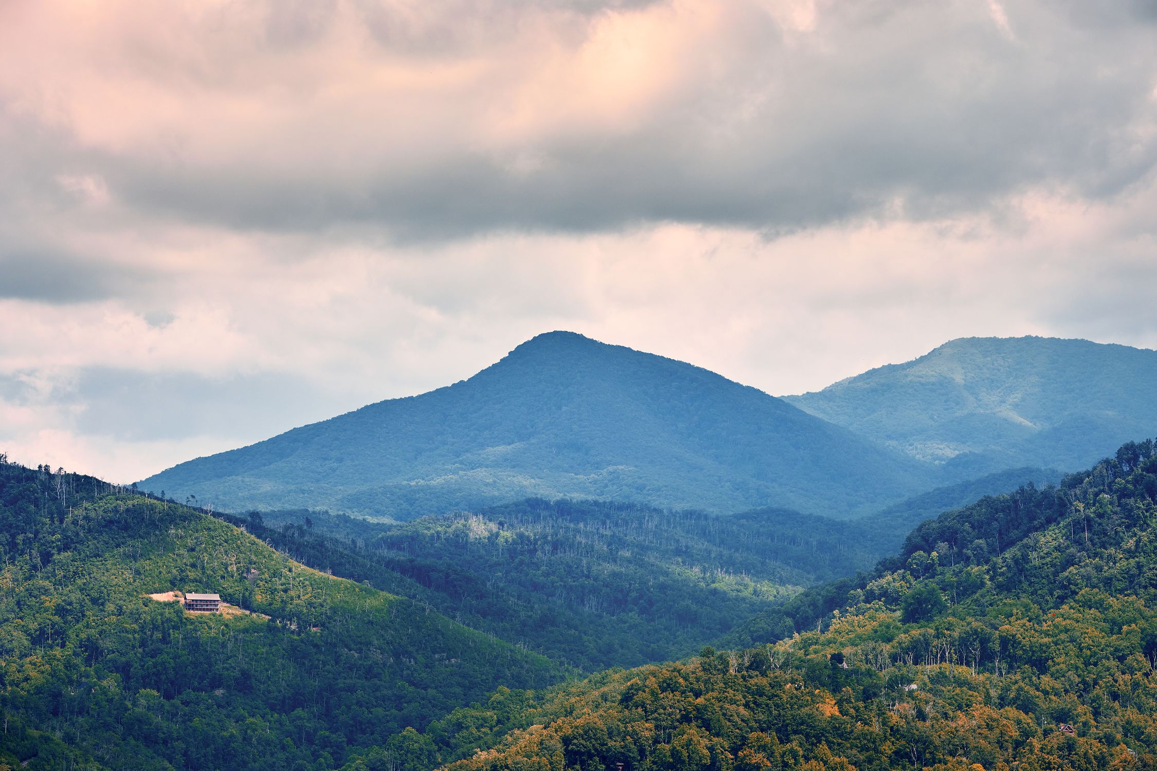 Breathtaking view of mountainous landscape with lush greenery under a dramatic cloudy sky.