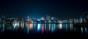 夜晚，五彩缤纷的灯光映照在平静的水面上，城市天际线令人惊叹
