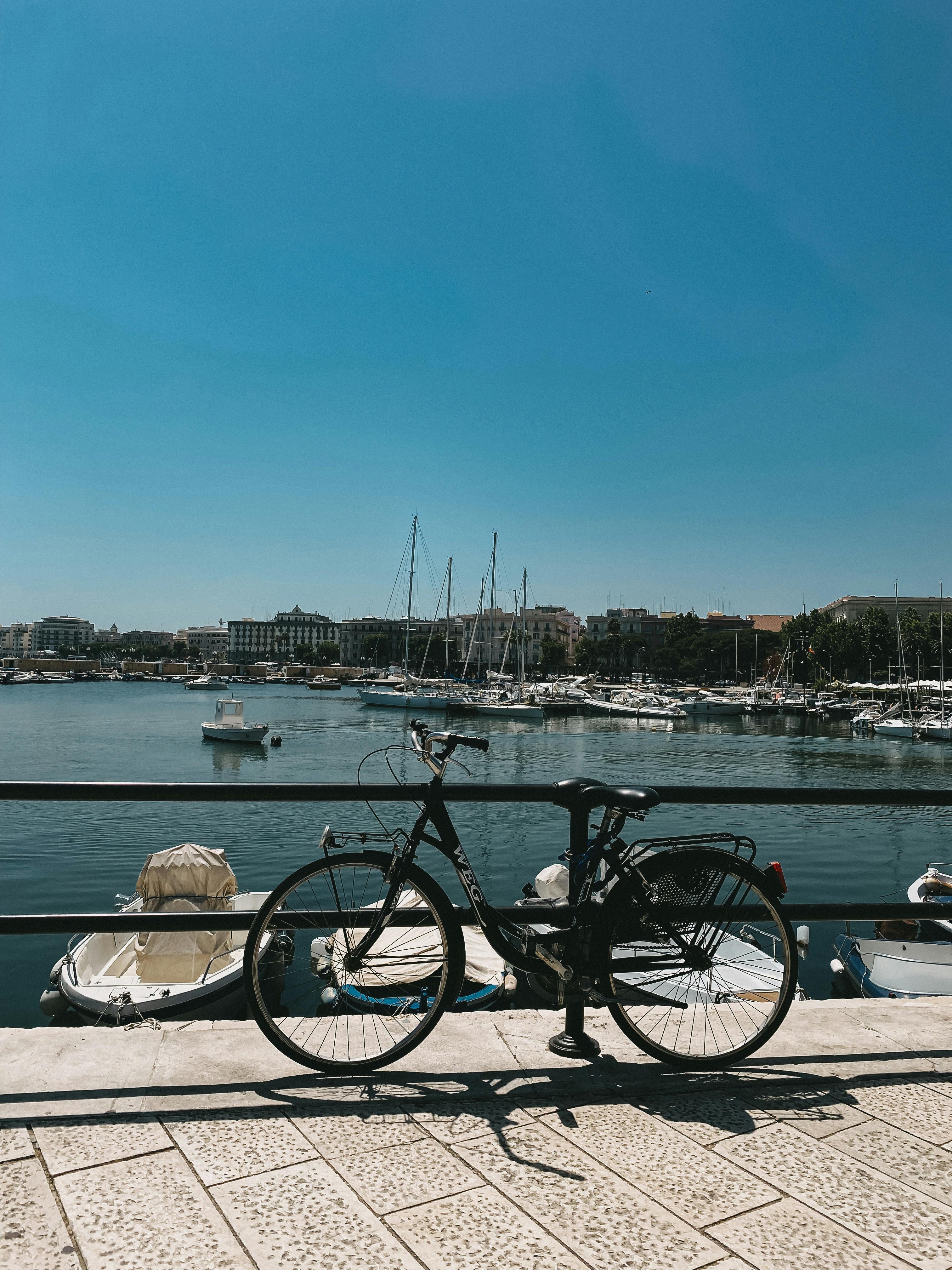 a bicycle parked on a pier with boats in the background