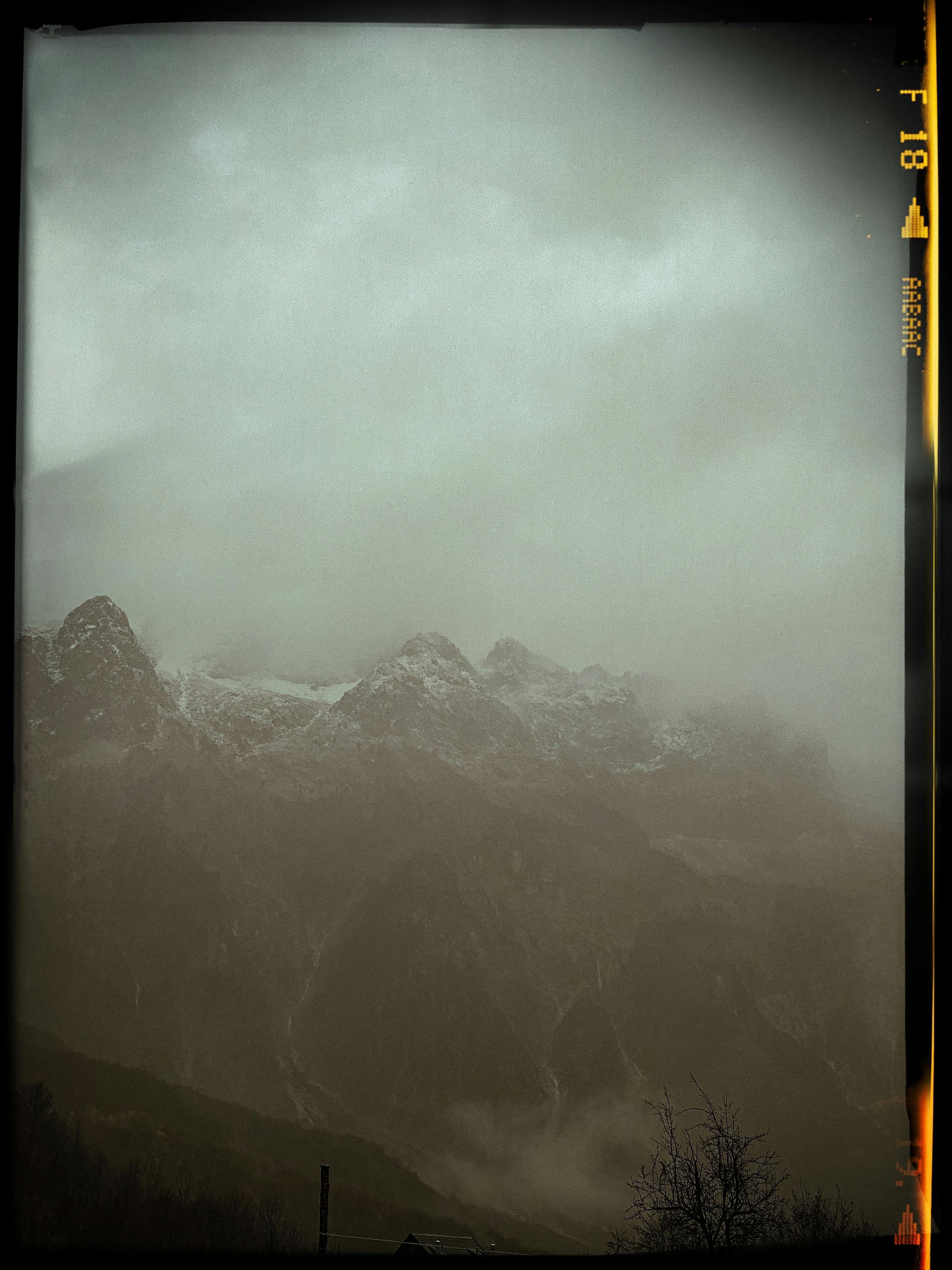 Dramatic mountain peaks shrouded in fog and mist, creating a moody atmosphere.