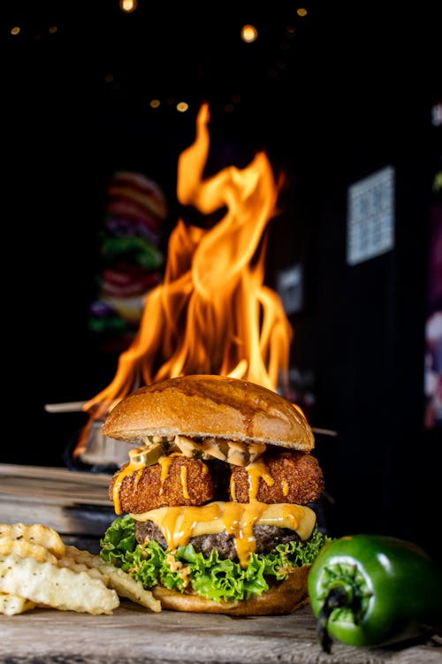 Free Delicious cheeseburger with jalapeño and fries, grilled to perfection with flames. Stock Photo
