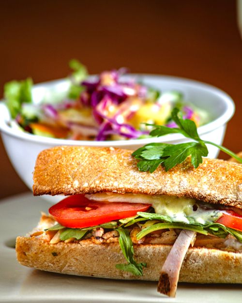 Free Tasty chicken sandwich with fresh vegetables and a vibrant salad, perfect for lunch. Stock Photo