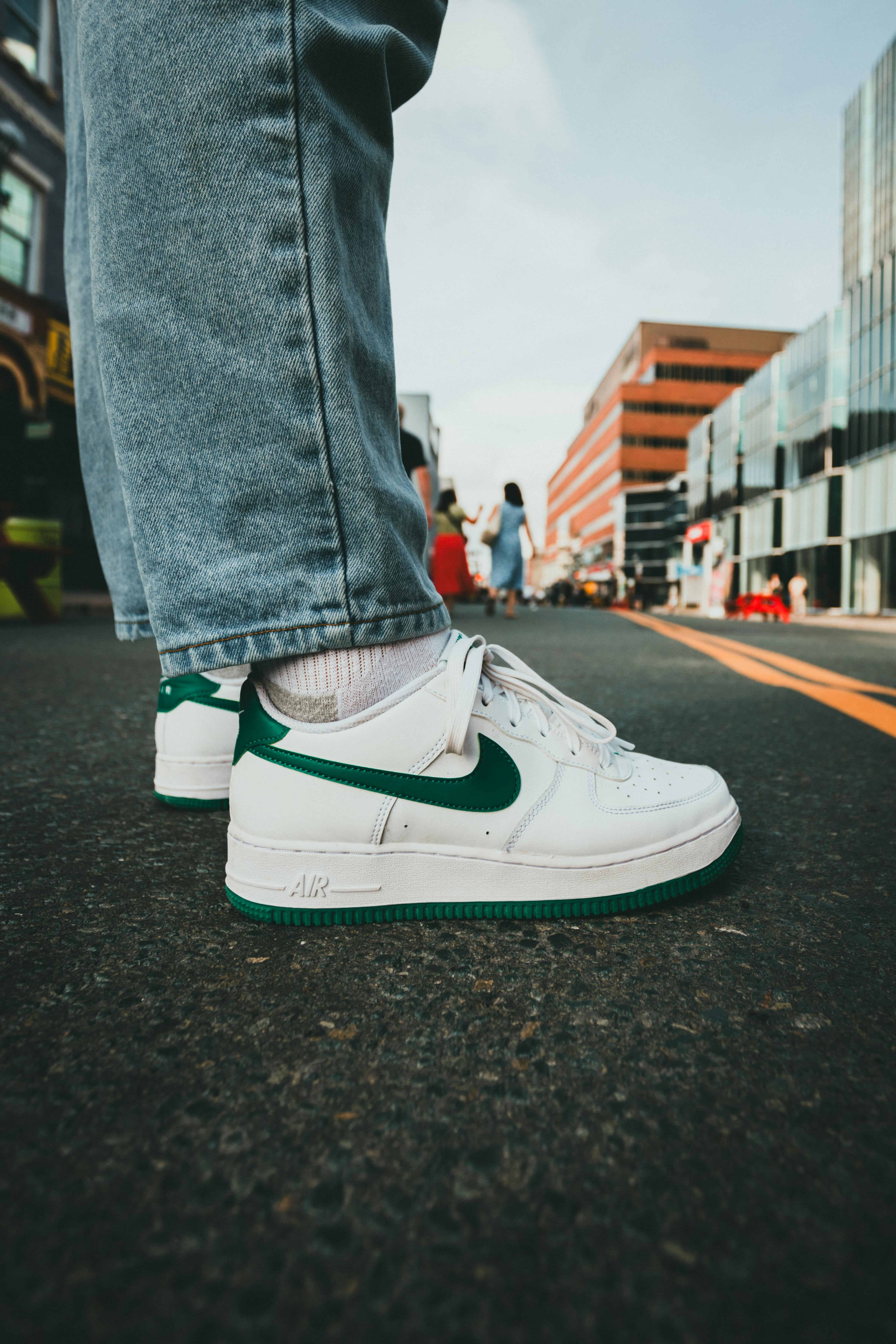 Close-up of casual sneakers on a city street with urban buildings in the background.