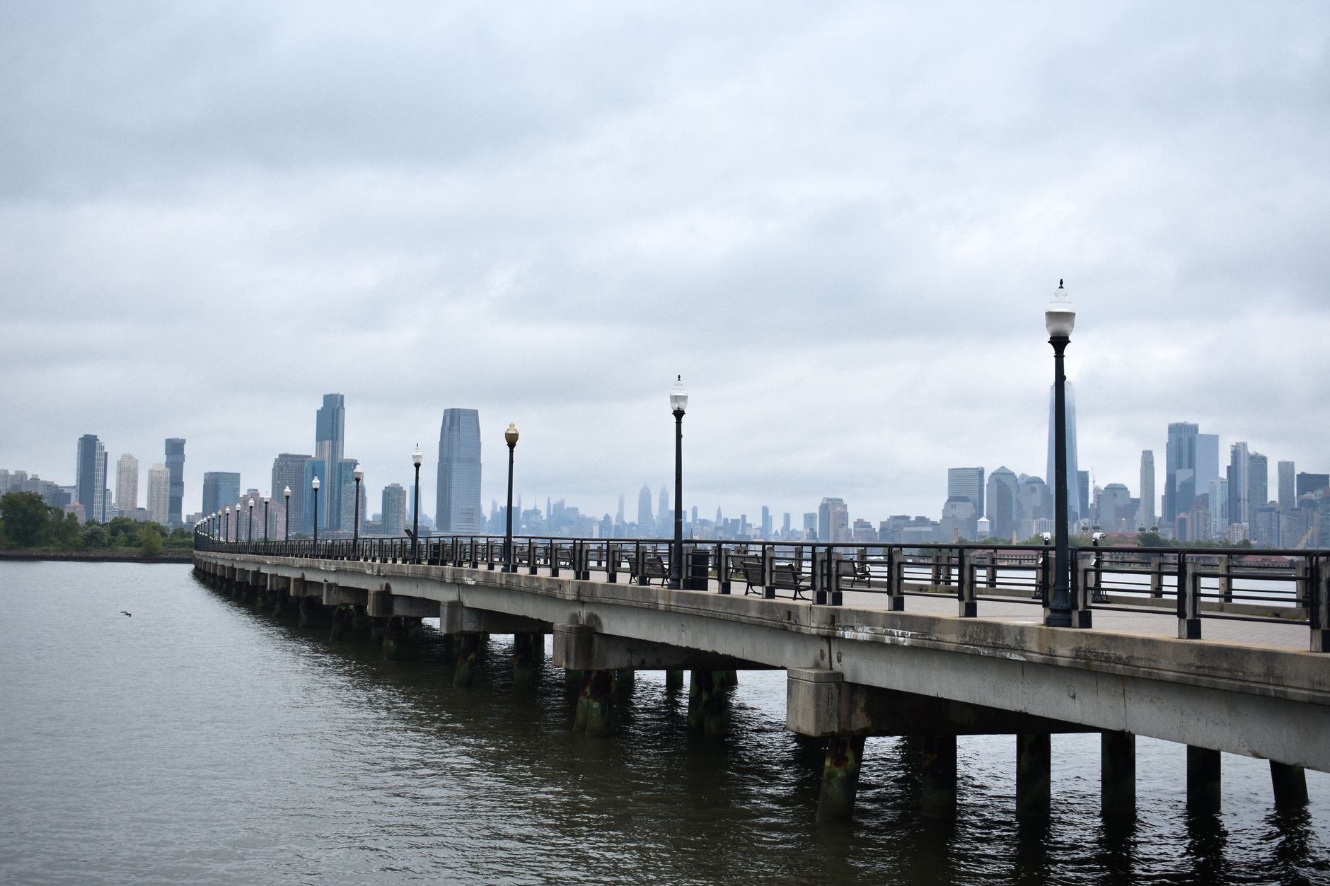 View of New York City skyline with a long pier under an overcast sky. Captivating urban landscape.