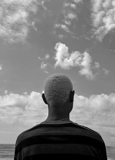 Black and white photo of a man gazing at the sea in Vila Velha, capturing a thoughtful moment.