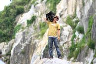 Man Standing on Rock While Holding Black Case