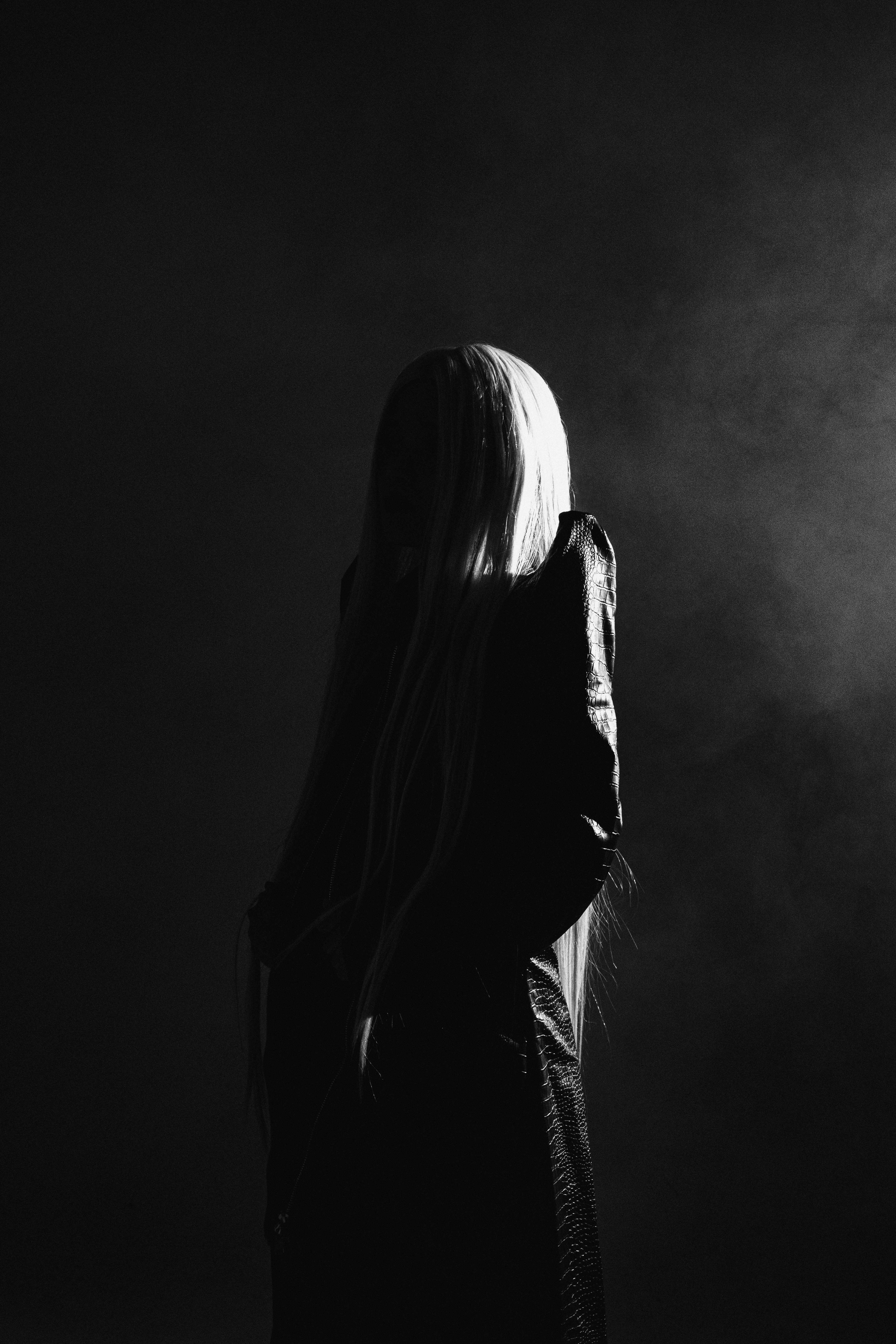 Stunning black and white silhouette of a woman with long hair in a mysterious studio setting.