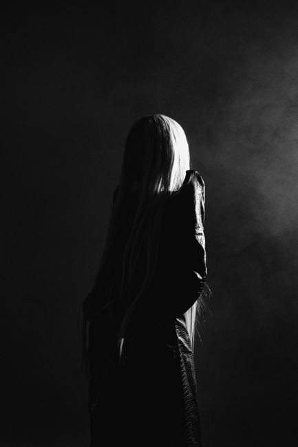 Stunning black and white silhouette of a woman with long hair in a mysterious studio setting.