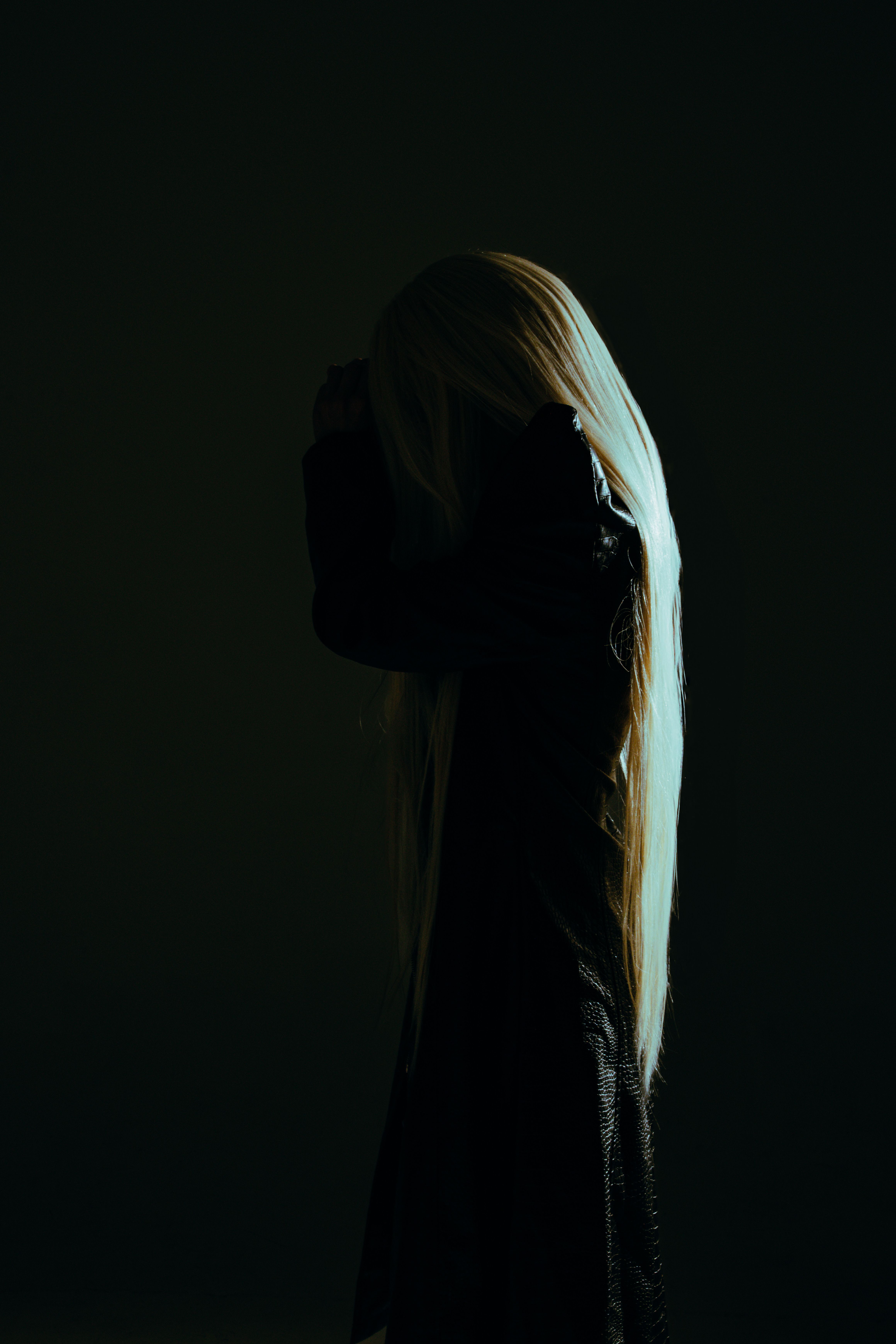 An artistic silhouette of a woman in a dark setting, highlighting fashion and mystery.