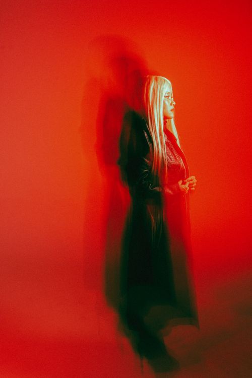 A woman in black standing in front of a red wall · Free Stock Photo