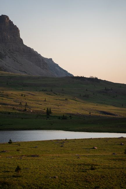 Sunrise over a quiet state park lake with empty campsites and tall pine trees
