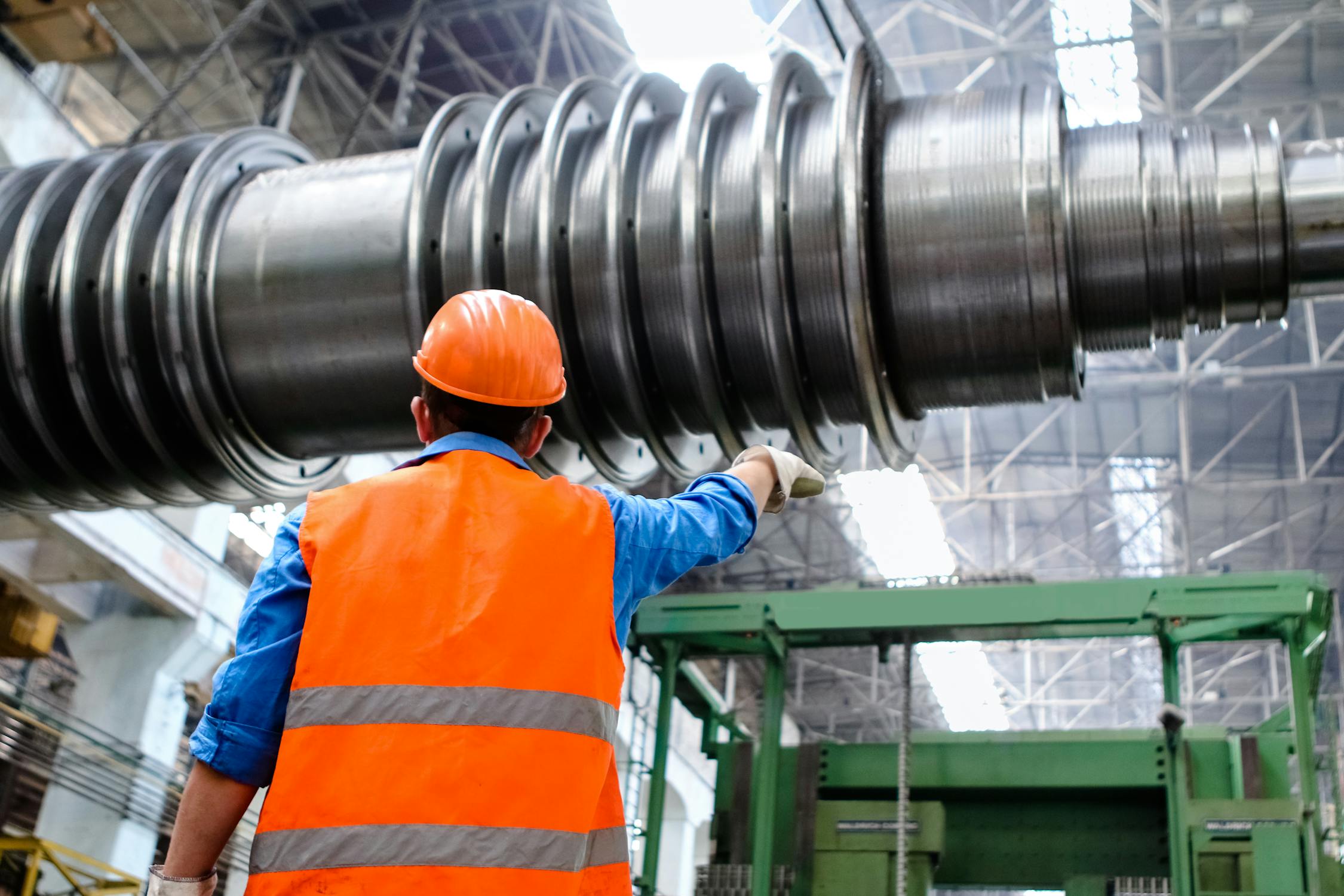 man wearing a hard hat and orange vest in a factory