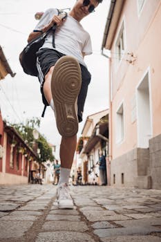Trendy male model poses on cobblestone street, showcasing urban streetwear style.