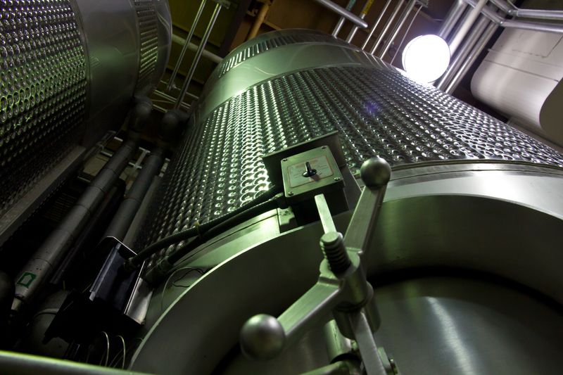 Low-angle shot of large stainless steel tanks inside a modern industrial facility