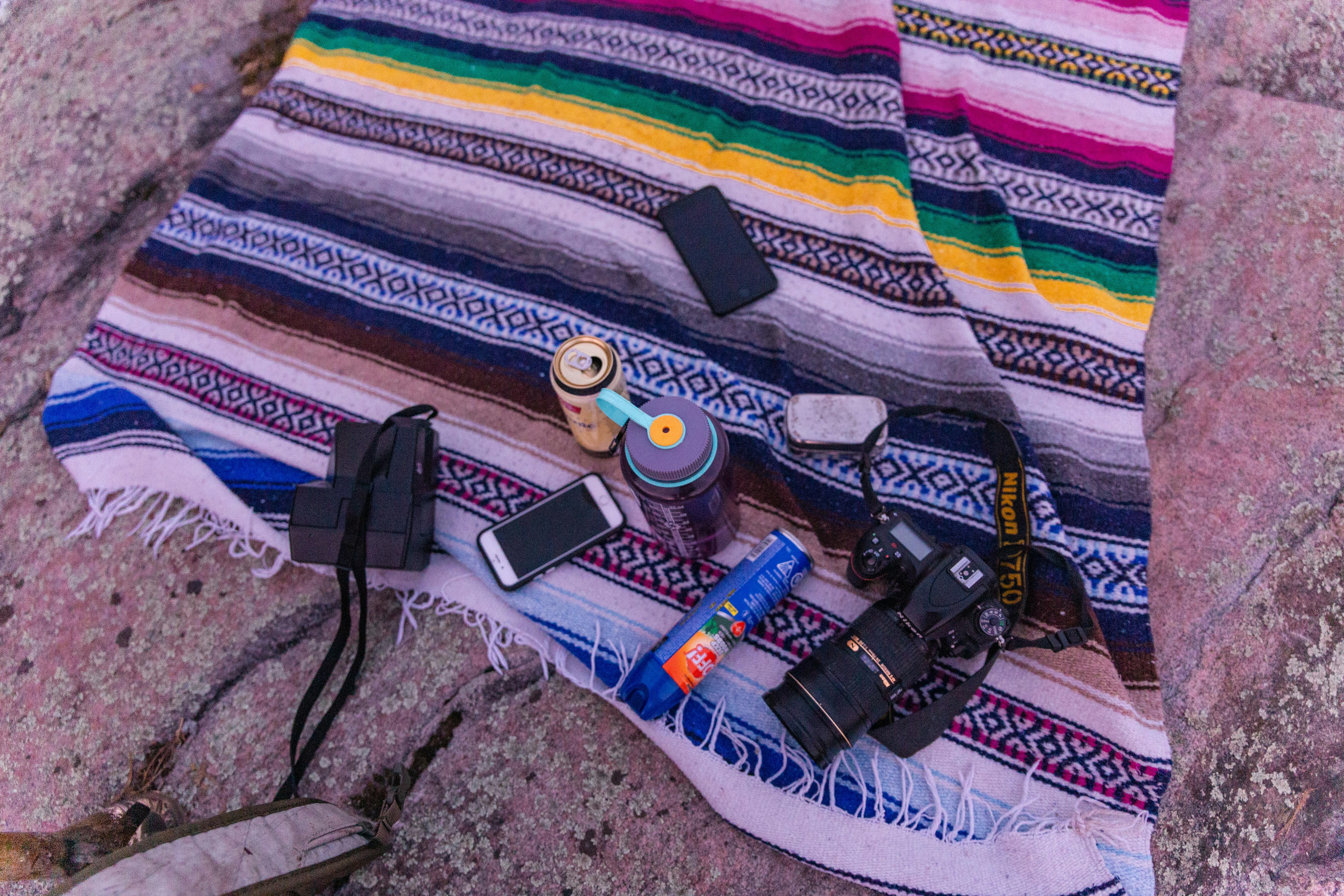 在图案毯子上，铺设有数码单反相机和小工具的户外色彩缤纷设置，适合摄影或休闲