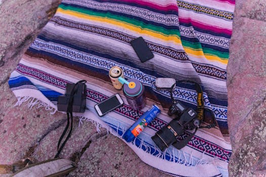 在图案毯子上，铺设有数码单反相机和小工具的户外色彩缤纷设置，适合摄影或休闲