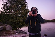 黄昏时分，一名年轻人在湖边拍照，周围是大自然