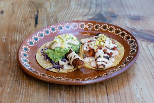 Close-up of traditional Mexican tacos with guacamole and salsa on a rustic wooden table.