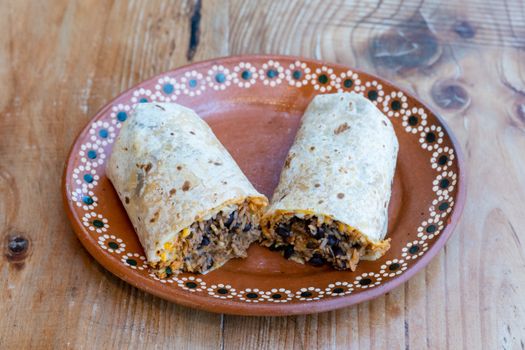 Tasty burrito with rice and beans on a decorative plate, perfect for breakfast or lunch.