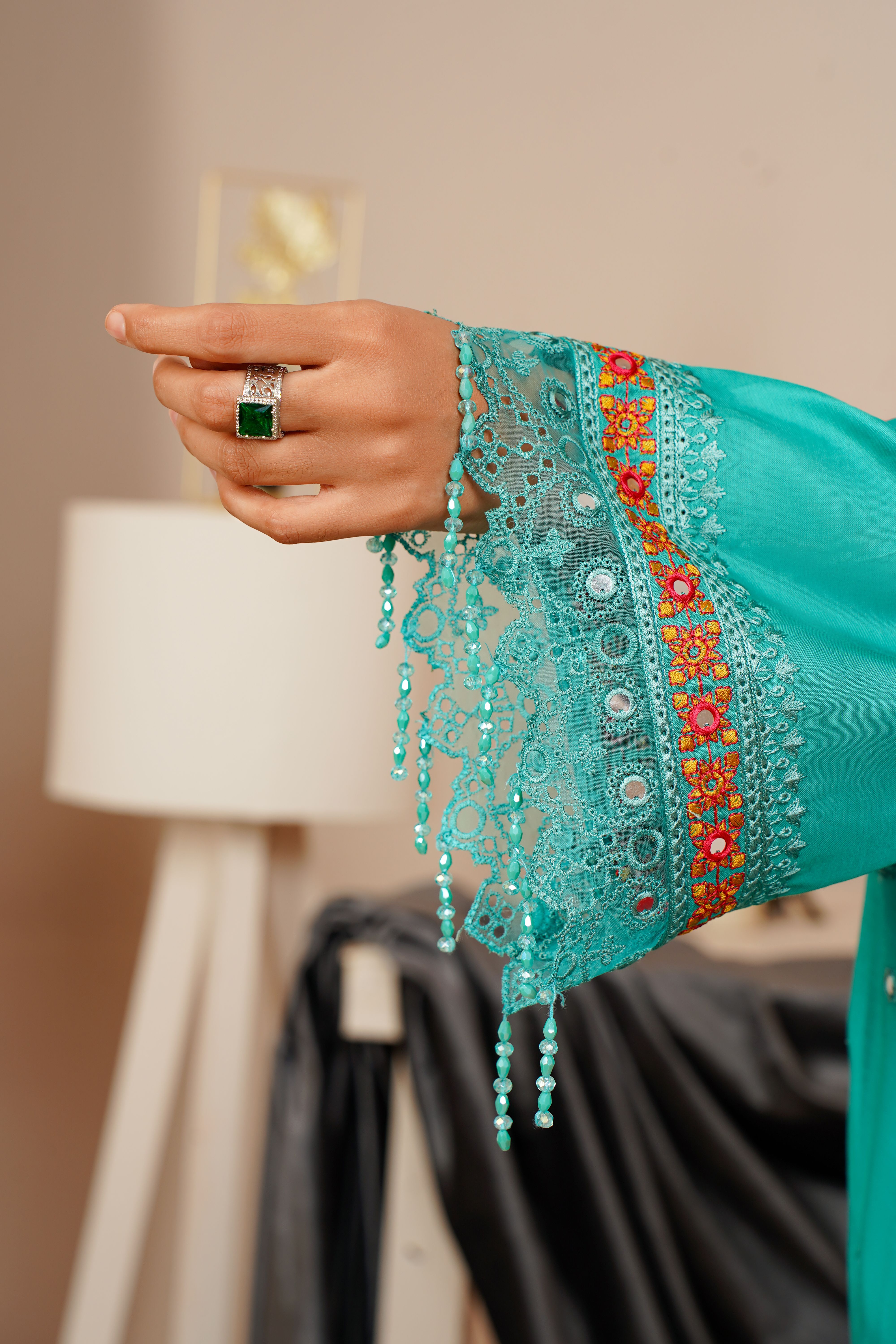 Close-up of an ornate sleeve with detailed embroidery and jewelry, showcasing elegance.