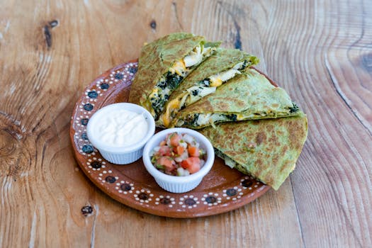 Delicious spinach and cheese quesadilla served with fresh salsa and cream.