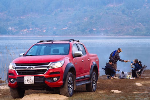 Scenic lake view with a red truck and group camping, enjoying the outdoors.
