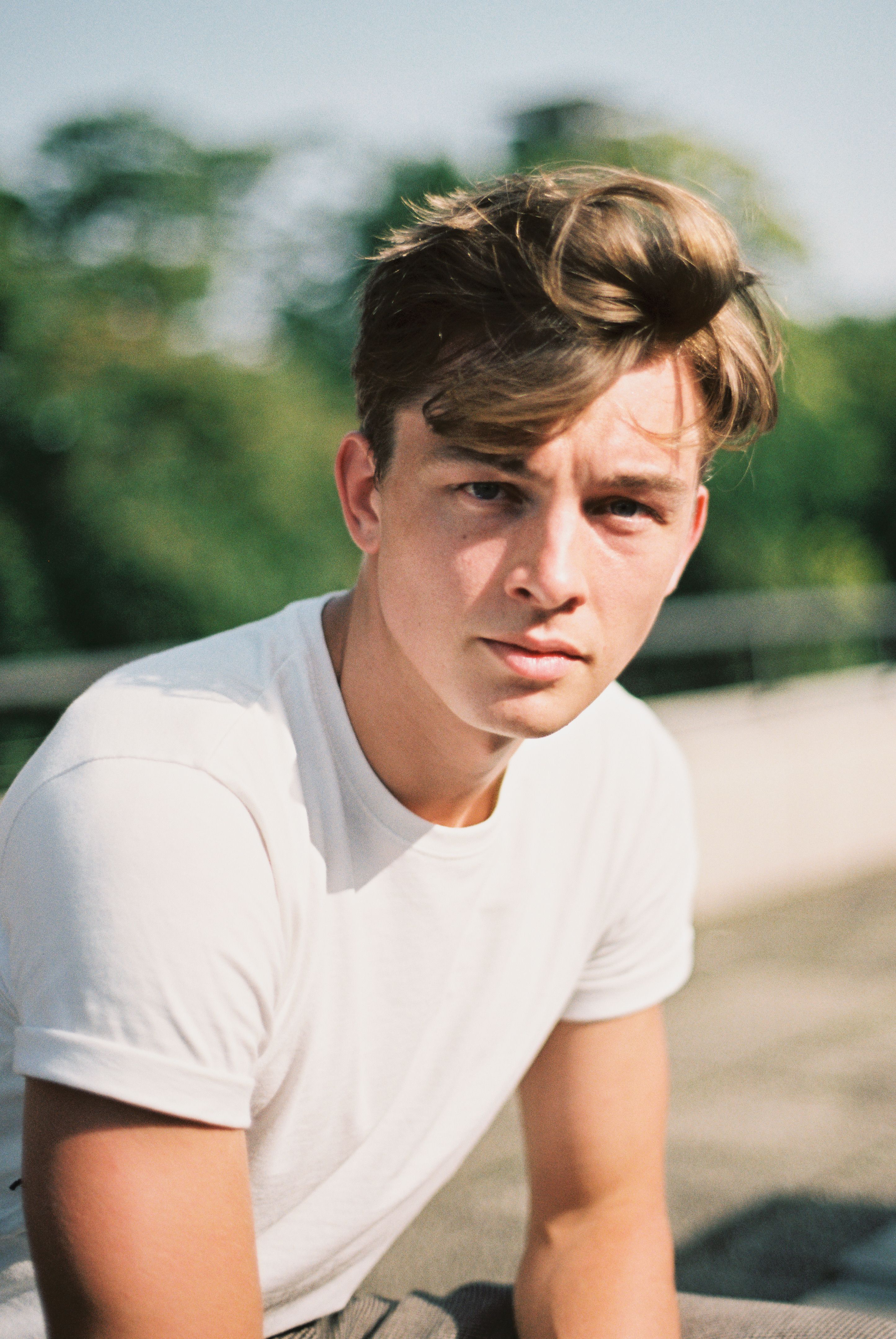 Portrait of a young man in casual attire enjoying a sunny day outdoors. Captures leisure and summer vibes.