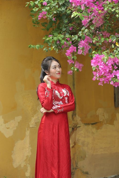 Free A woman in a red traditional Asian dress surrounded by pink flowers outdoors. Stock Photo