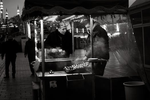 Captivating black and white scene of a street vendor selling roast chestnuts at night.