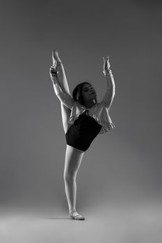 Black and white portrait of a young ballerina in a studio showcasing her flexibility and poise.