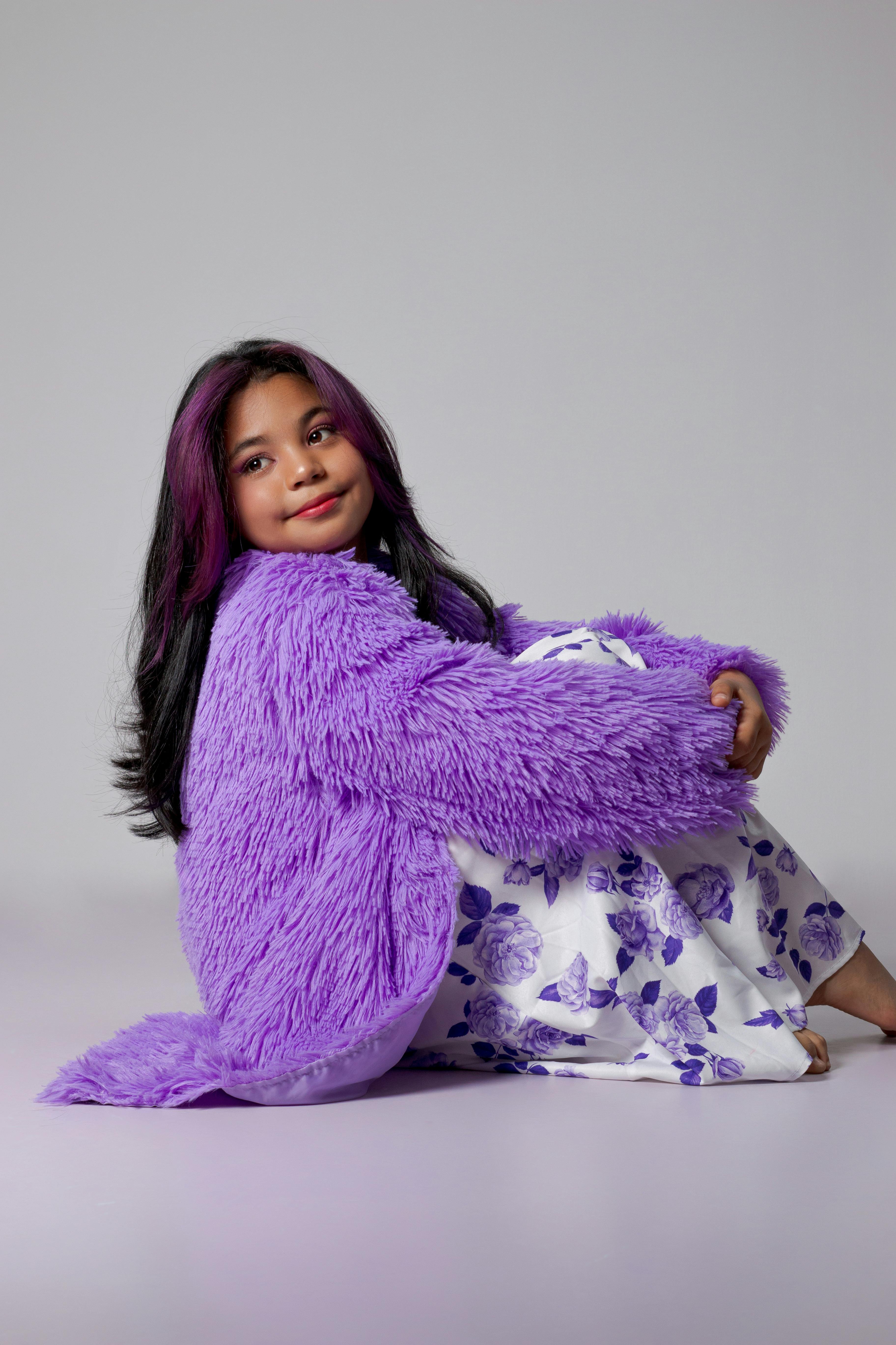 Delightful portrait of a young girl in a purple jacket and floral dress.