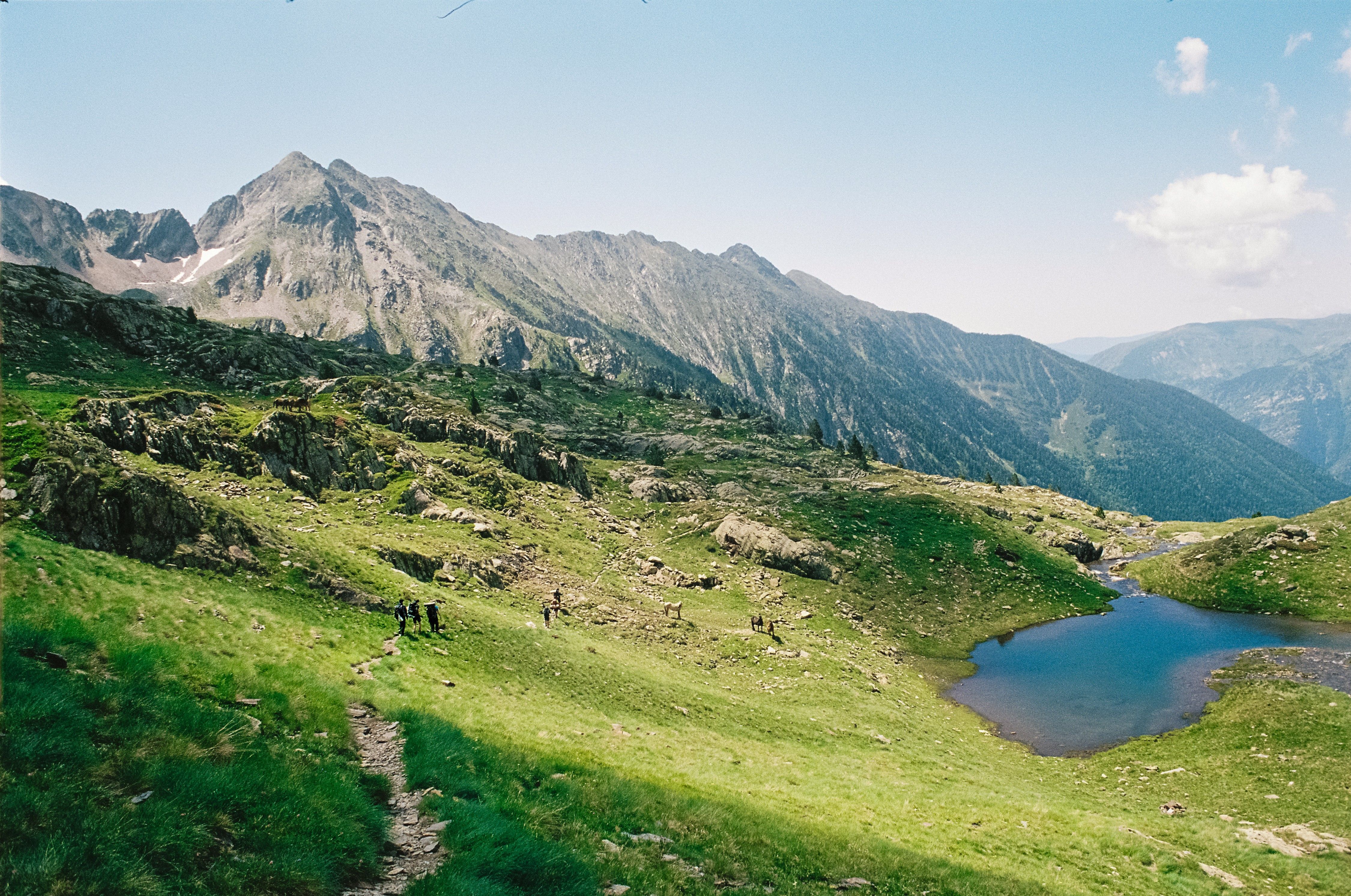 A mountain lake surrounded by green grass and mountains · Free Stock Photo