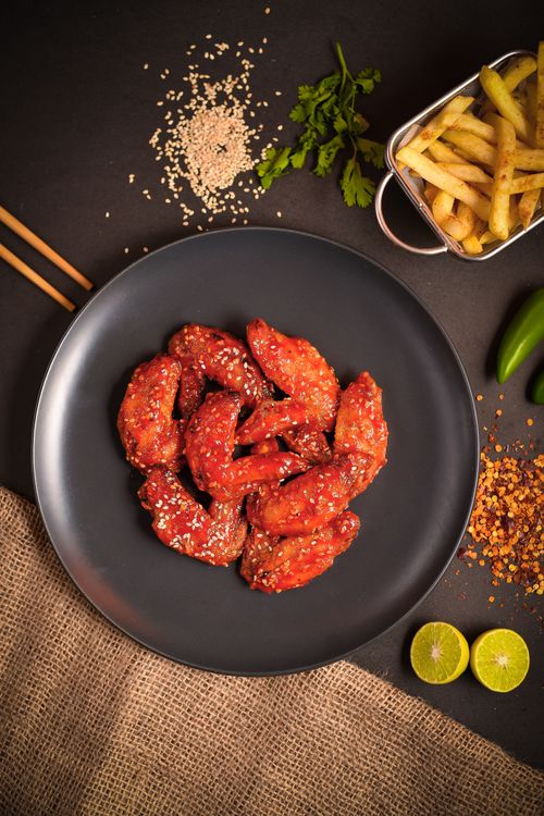 Free Delicious spicy chicken wings garnished with sesame seeds served with crispy French fries. Stock Photo