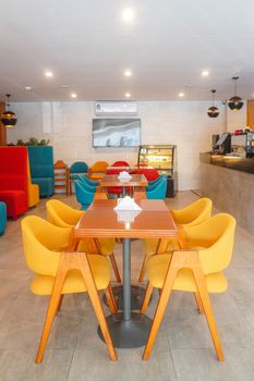 Bright and colorful modern cafe interior with mixed seating options and minimalistic decor.