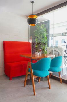 Modern cafe interior in Islamabad featuring a vibrant red sofa and teal chairs.