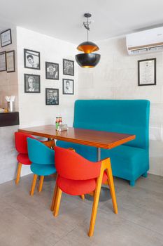 Bright and inviting café seating area with colorful chairs and framed art on the walls.