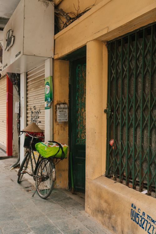 Free A vintage bicycle leans against a building in Hanoi's bustling streets, capturing urban life. Stock Photo