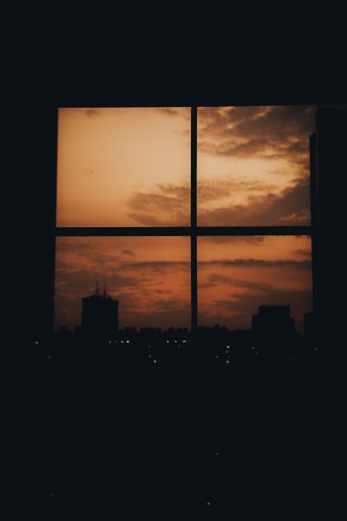 Free Capture of Jakarta skyline silhouetted against a vibrant sunset through a window. Stock Photo