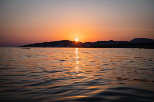Free Capture of a serene sunset over Ulcinj beach, Montenegro, reflecting vibrant colors on the water. Stock Photo