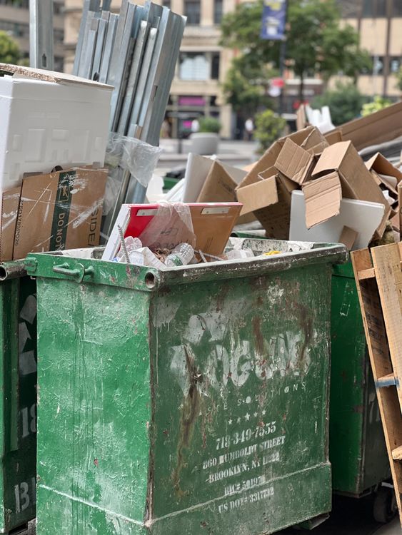A green trash can with cardboard boxes in it · Free Stock Photo